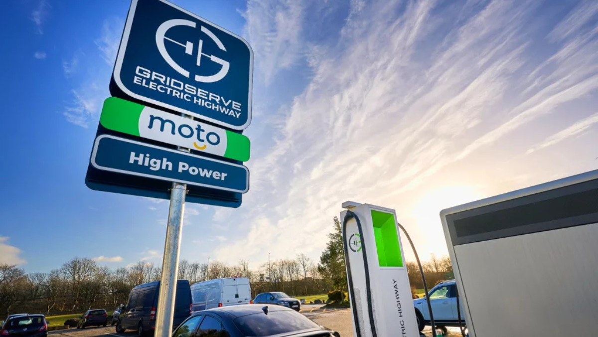 GRIDSERVE EV charging station and signage at a UK service area under a bright sky.