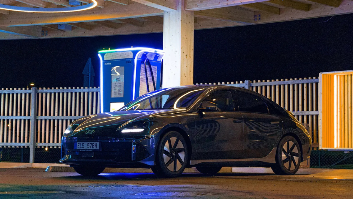 Electric vehicle charging station with a parked EV at a brightly lit destination site