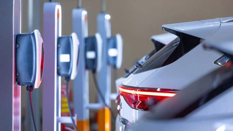 Electric car plugged into a row of indoor EV charging stations